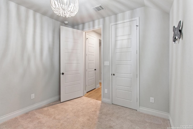 unfurnished bedroom with a notable chandelier and light colored carpet