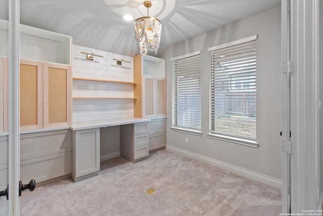 unfurnished office with light carpet, a notable chandelier, and built in desk