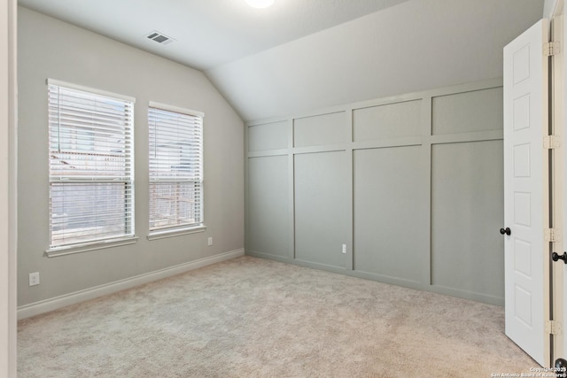 unfurnished bedroom with vaulted ceiling and light carpet