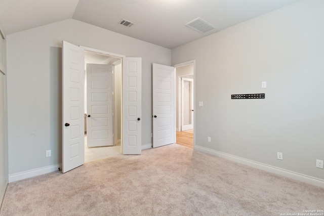 unfurnished bedroom featuring light colored carpet and vaulted ceiling