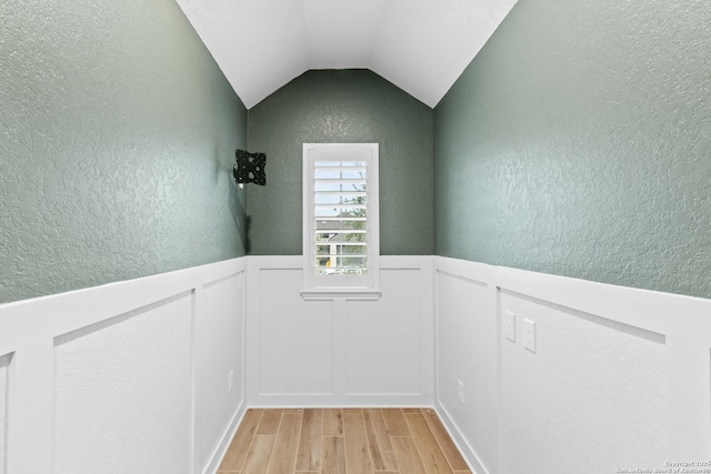 empty room with vaulted ceiling and light hardwood / wood-style flooring