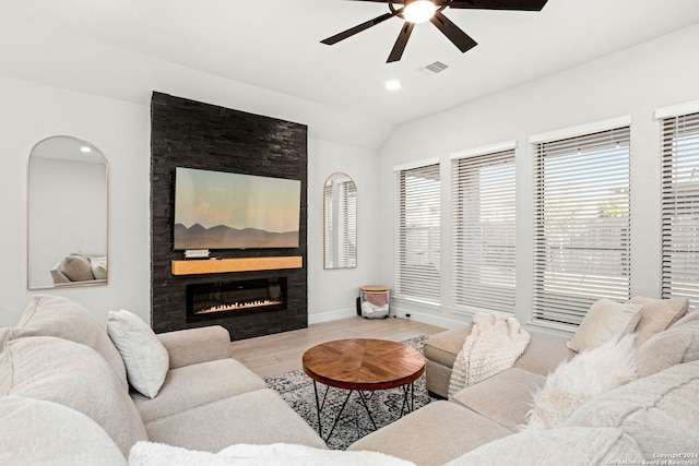 living room featuring plenty of natural light, lofted ceiling, a fireplace, and light hardwood / wood-style flooring