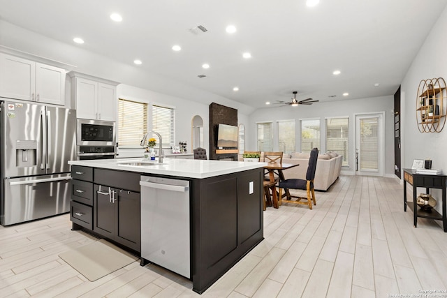 kitchen featuring sink, white cabinetry, a kitchen island with sink, stainless steel appliances, and light wood-type flooring