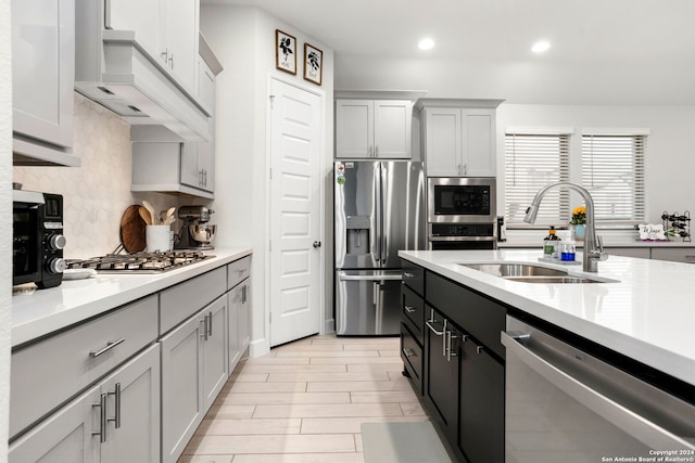 kitchen with sink, decorative backsplash, stainless steel appliances, and custom range hood