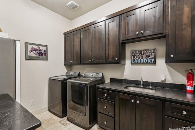 washroom with sink, washing machine and dryer, and cabinets