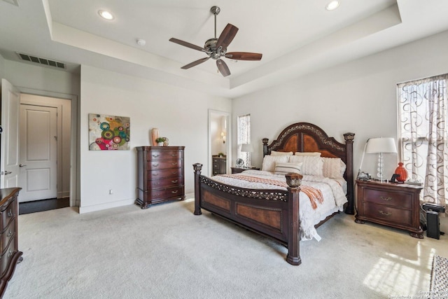 carpeted bedroom with ceiling fan and a tray ceiling