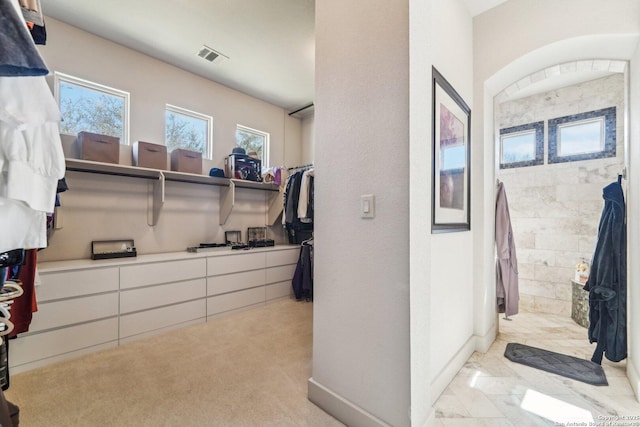 walk in closet featuring light colored carpet