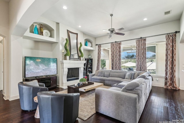 living room with ceiling fan, dark hardwood / wood-style flooring, and built in shelves