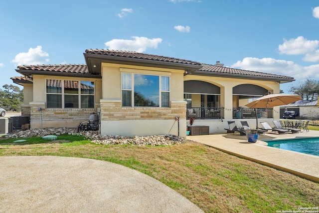 back of house with a fenced in pool, a patio, and a lawn