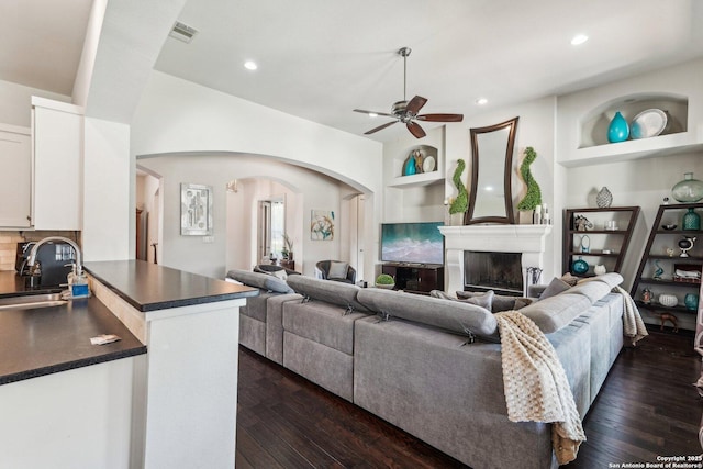 living room featuring dark wood-type flooring, ceiling fan, sink, and built in features