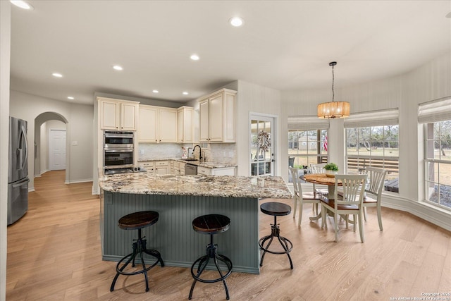 kitchen with appliances with stainless steel finishes, a sink, decorative backsplash, and light stone countertops