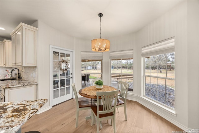 dining space featuring a chandelier, light wood-style flooring, and baseboards