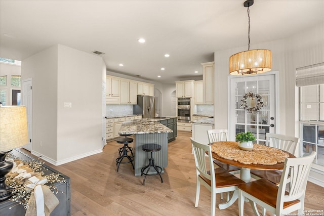 kitchen featuring a center island, cream cabinetry, visible vents, appliances with stainless steel finishes, and light wood-style floors