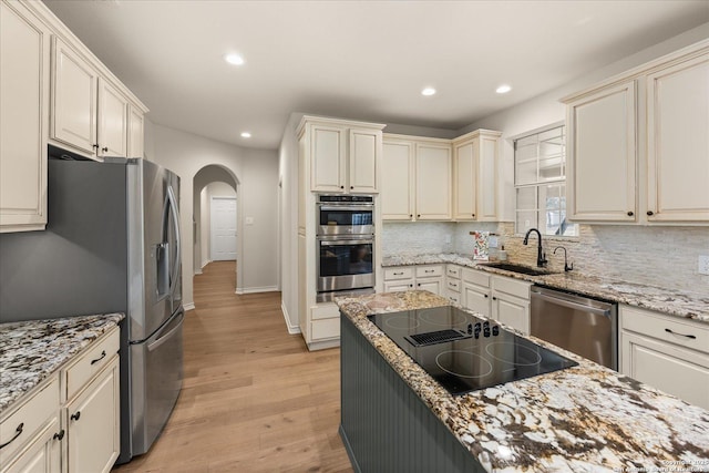 kitchen with light wood finished floors, tasteful backsplash, recessed lighting, appliances with stainless steel finishes, and a sink