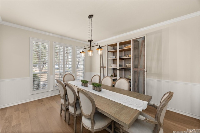 dining area with ornamental molding, wainscoting, and wood finished floors