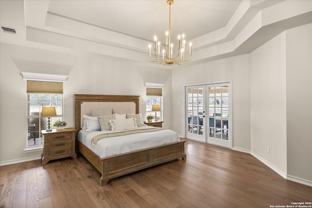 bedroom with a tray ceiling, french doors, visible vents, wood finished floors, and access to outside