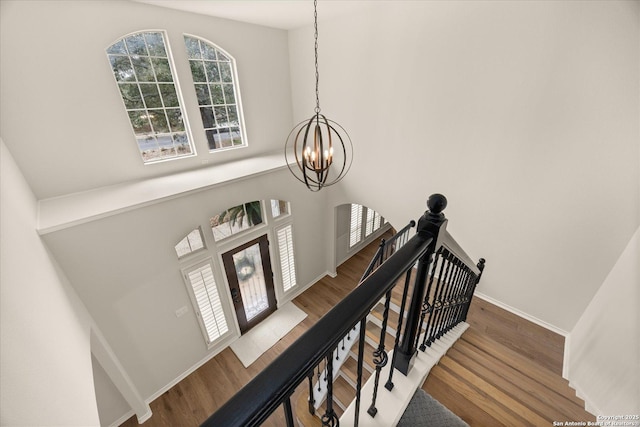 stairs featuring a chandelier, baseboards, and wood finished floors