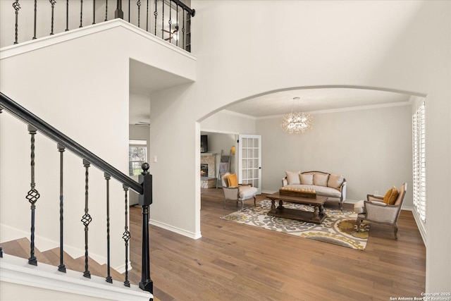 entrance foyer featuring a towering ceiling, ornamental molding, wood finished floors, stairs, and a fireplace