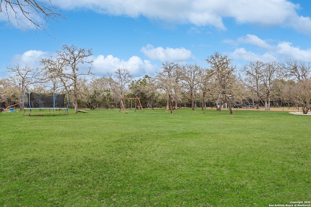 view of yard featuring a trampoline and playground community