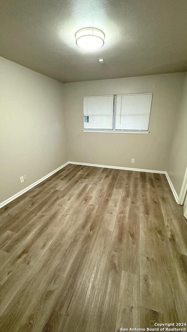 unfurnished room featuring wood-type flooring and a textured ceiling