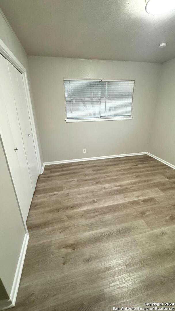 unfurnished bedroom featuring hardwood / wood-style flooring, a closet, and a textured ceiling