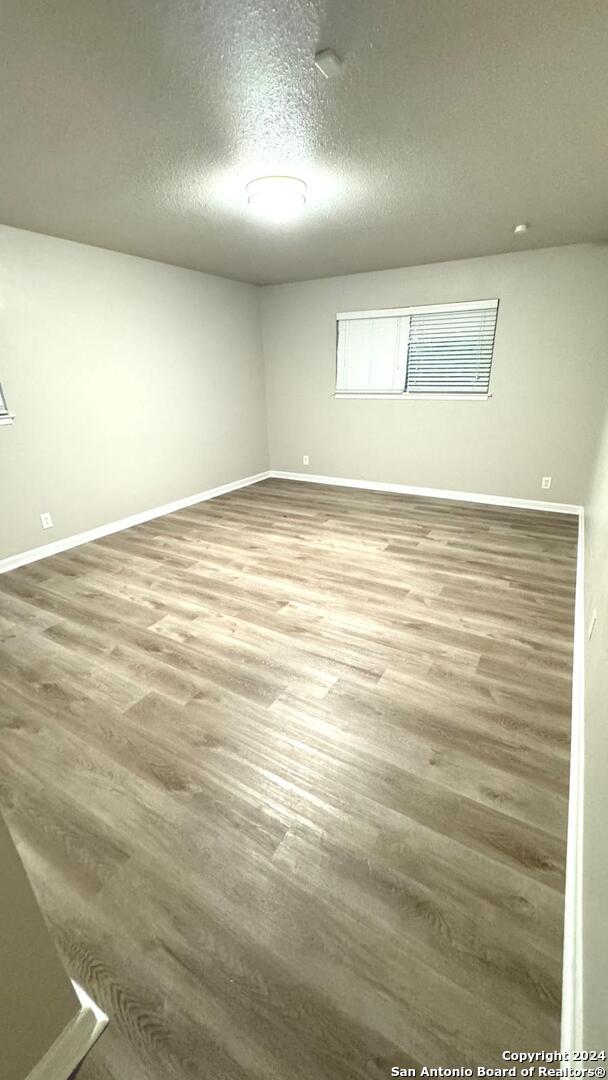 empty room featuring wood-type flooring and a textured ceiling