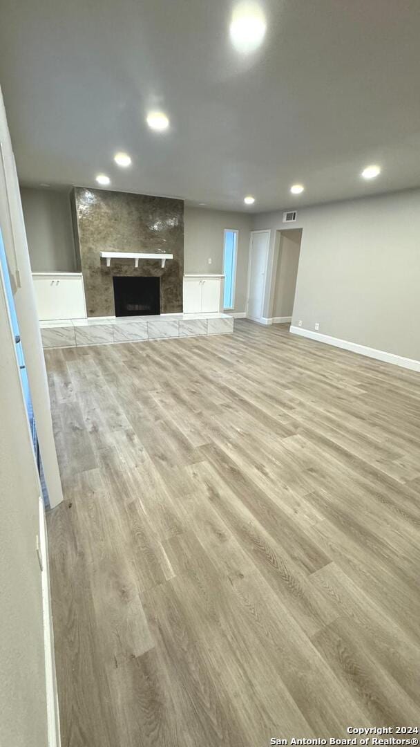 unfurnished living room with hardwood / wood-style floors and a large fireplace