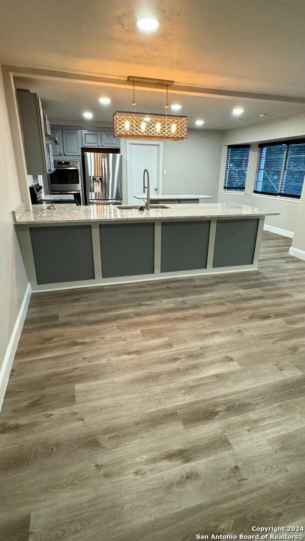 kitchen featuring pendant lighting, dark hardwood / wood-style flooring, kitchen peninsula, and stainless steel refrigerator with ice dispenser