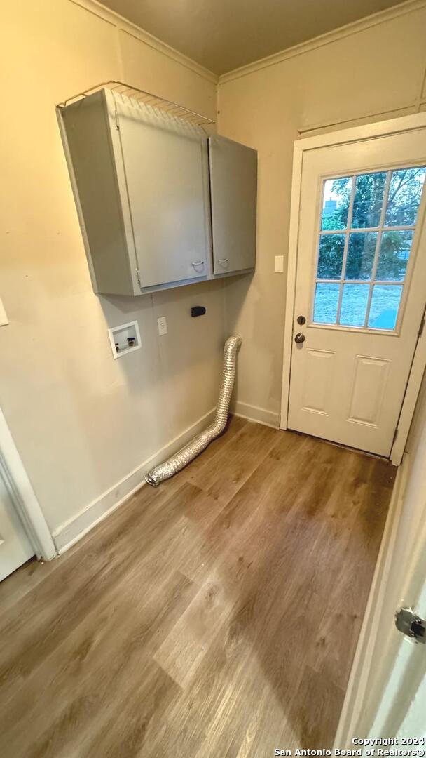 washroom featuring cabinets, wood-type flooring, hookup for a washing machine, and crown molding