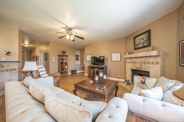 living room with ceiling fan, light hardwood / wood-style floors, and a tile fireplace