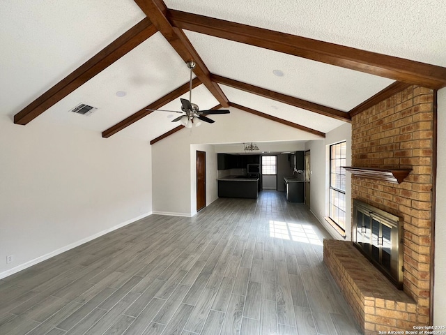 unfurnished living room with lofted ceiling with beams, a brick fireplace, a textured ceiling, dark hardwood / wood-style floors, and a baseboard heating unit