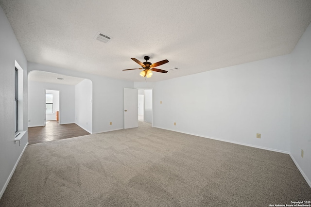 empty room with ceiling fan, a textured ceiling, and carpet