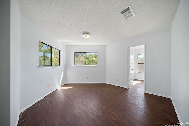 empty room with dark wood-type flooring and a textured ceiling