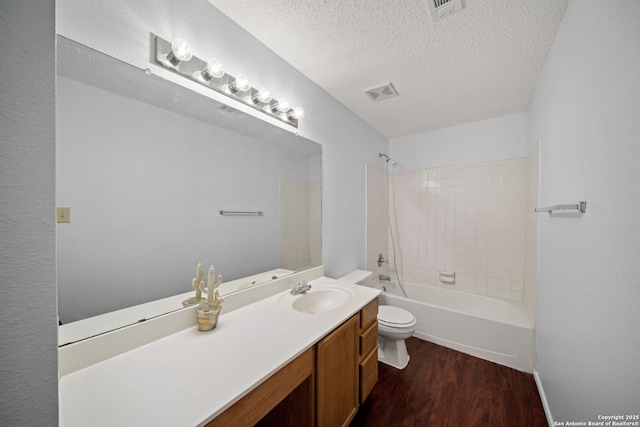 full bathroom with vanity, wood-type flooring, a textured ceiling, toilet, and tiled shower / bath