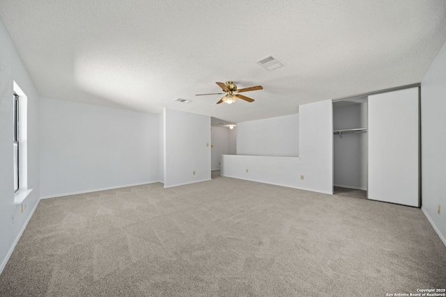 unfurnished bedroom with ceiling fan, a closet, light carpet, and a textured ceiling