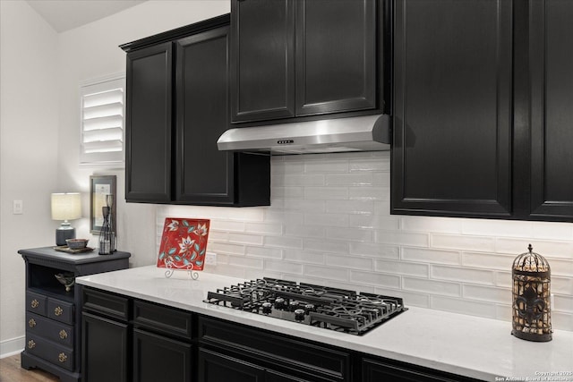 kitchen featuring dark cabinetry and under cabinet range hood