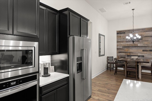 kitchen with stainless steel appliances, light countertops, visible vents, and dark cabinets