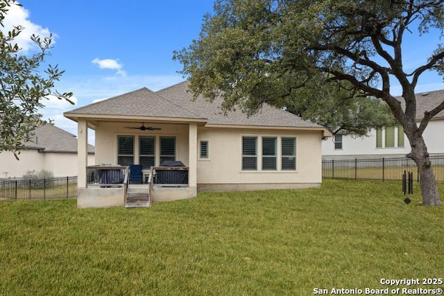 back of house featuring a yard, a fenced backyard, ceiling fan, and stucco siding