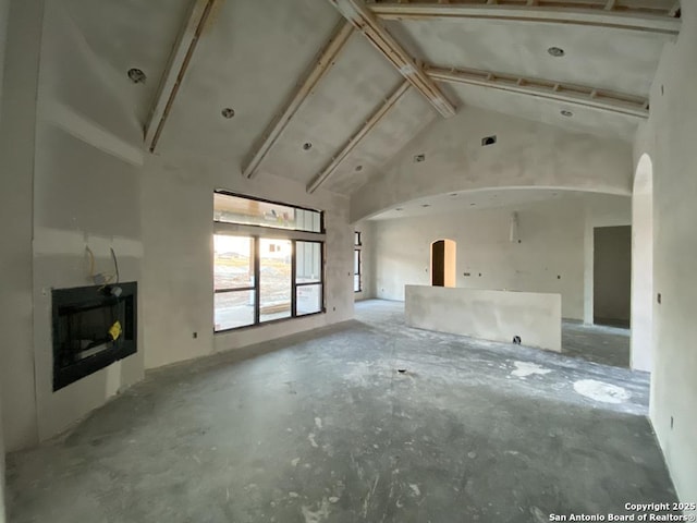 unfurnished living room featuring beam ceiling and high vaulted ceiling