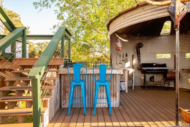 wooden deck featuring exterior bar and a grill