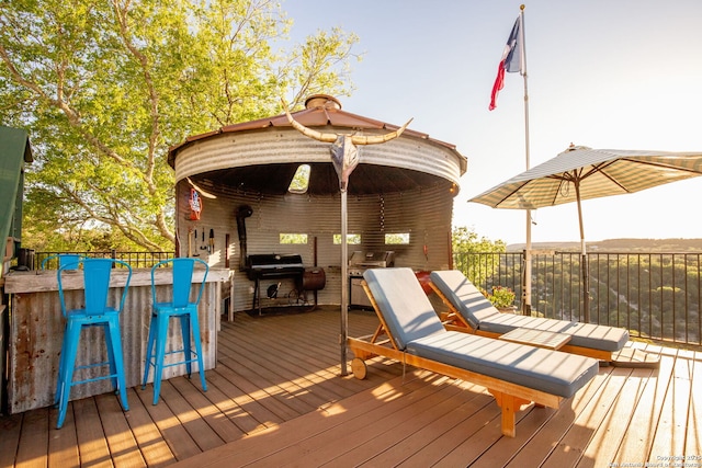 wooden deck featuring area for grilling and a bar