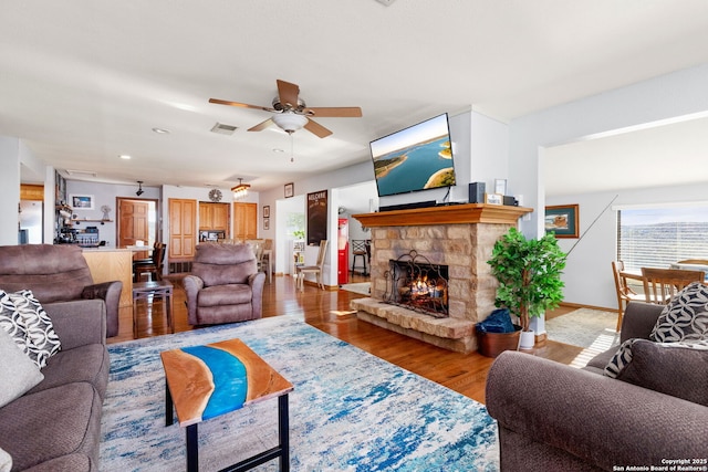 living room with a fireplace, light hardwood / wood-style flooring, and ceiling fan