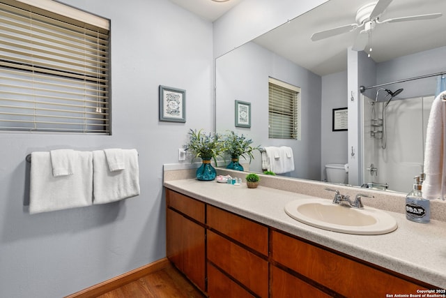 bathroom with hardwood / wood-style floors, vanity, ceiling fan, walk in shower, and toilet