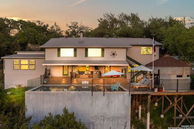 back house at dusk with a pool side deck