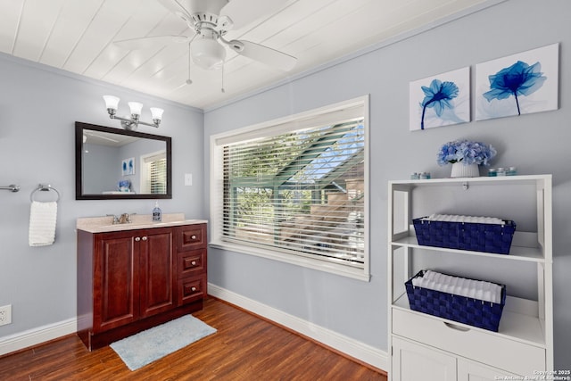 bathroom with crown molding, ceiling fan with notable chandelier, hardwood / wood-style floors, and vanity