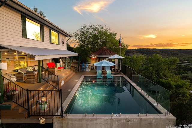 pool at dusk featuring a wooden deck