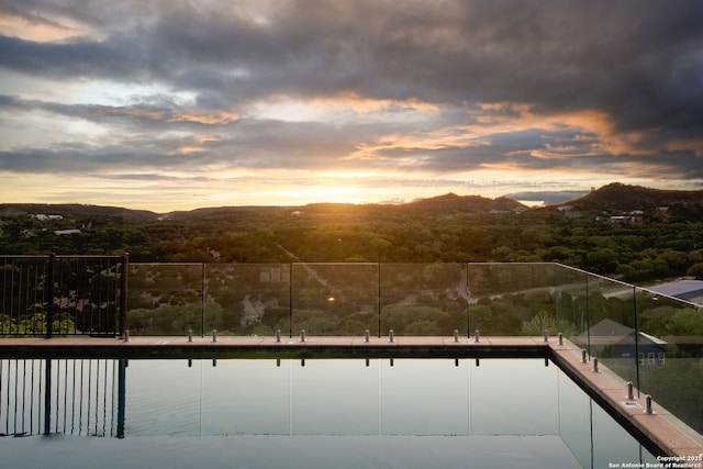 pool at dusk featuring a water and mountain view