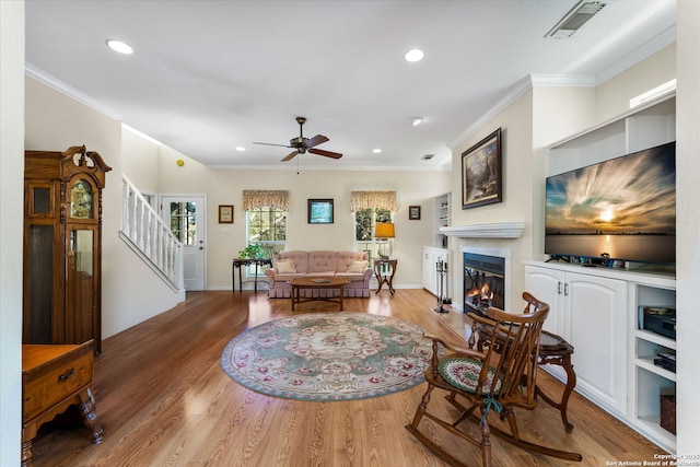 living room with hardwood / wood-style flooring, ornamental molding, and ceiling fan