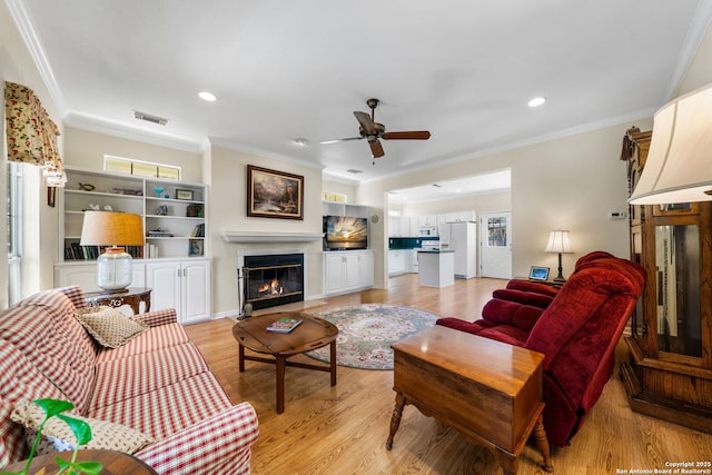 living room featuring crown molding, ceiling fan, and light hardwood / wood-style flooring