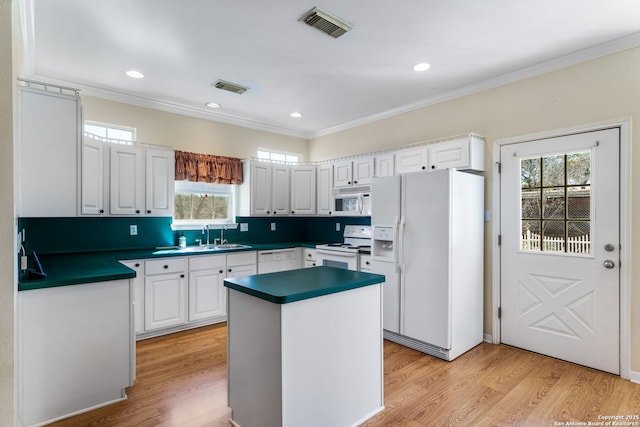 kitchen with white appliances, light wood-type flooring, a kitchen island, and white cabinets